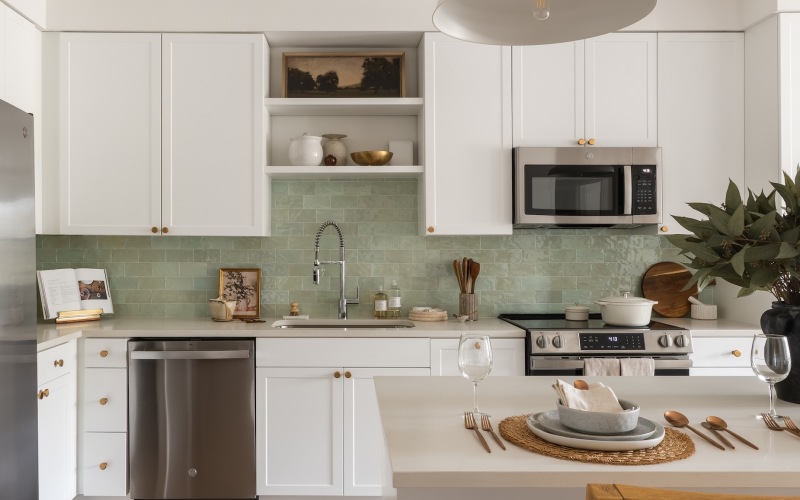 A kitchen with white cabinets and stainless steel appliances at The Mia North Austin apartments.